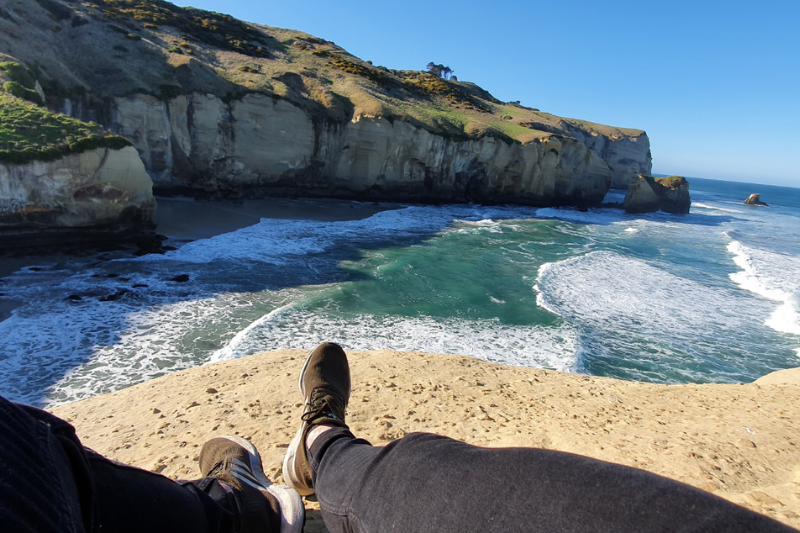 On top of the natural sandstone bridge over the ocean at Tunnel Beach
